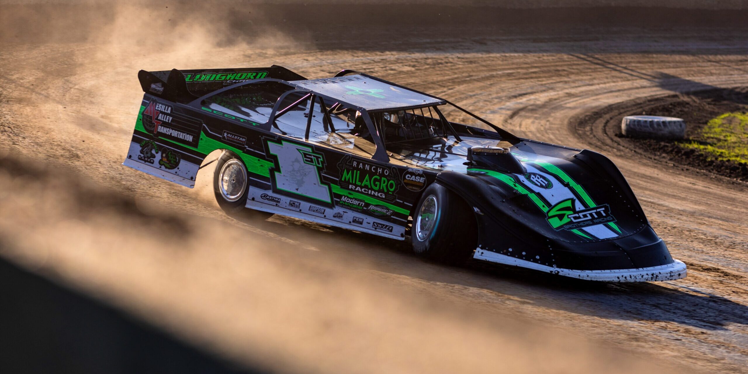 A race car in the middle of a turn on a dirt race track.