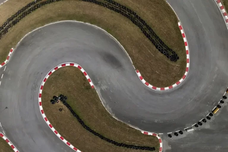 aerial-top-view-race-kart-track-track-for-auto-ra-2023-11-27-15-54-31-utc-min Aerial top view of a "S" curve set of turns on a race kart track for auto racing.