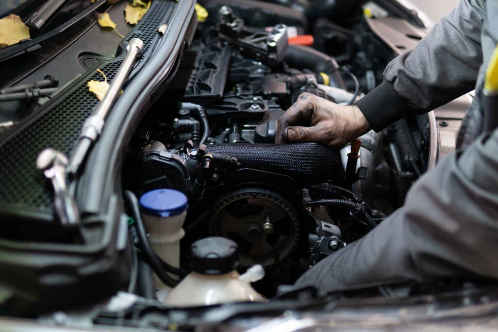 A car mechanic does service on a car.