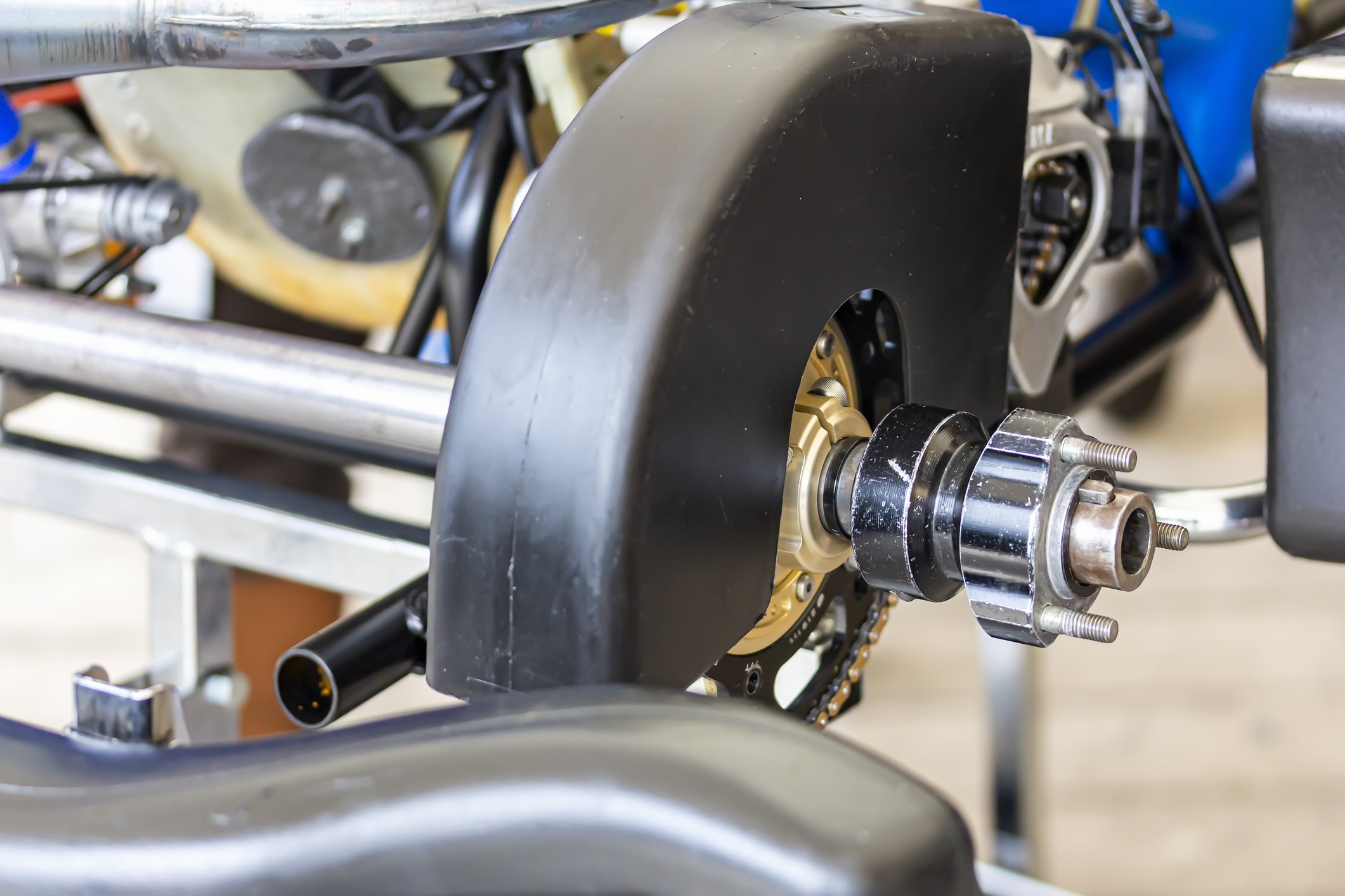 Standard rear wheel hubs with spindle axle of a mini race car is serviced at a service stand.